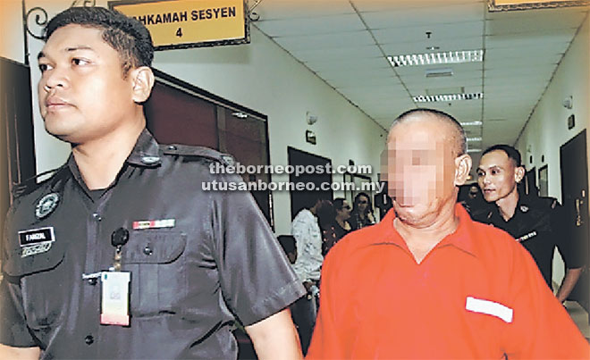  Tertuduh yang memakai pakaian seragam penjara berwarna merah diiringi oleh pegawai Jabatan Penjara.
