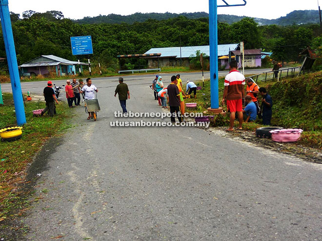  Penduduk kampung membersihkan kawasan gerbang pintu masuk ke kampung itu.
