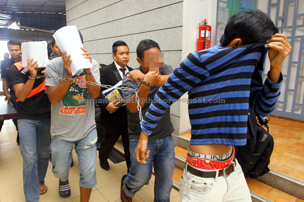  Empat lelaki diiringi anggota polis untuk didakwa di Mahkamah Sesyen Kangar semalam berhubung kes memiliki senjata api. — Gambar Bernama