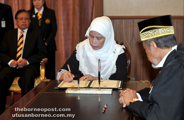  Jamilah menandatangani dokumen di hadapan Asfia (kanan) sambil disaksikan Abang Johari (belakang) selepas mengangkat sumpah sebagai ADUN Tanjong Datu di Kuching, semalam.