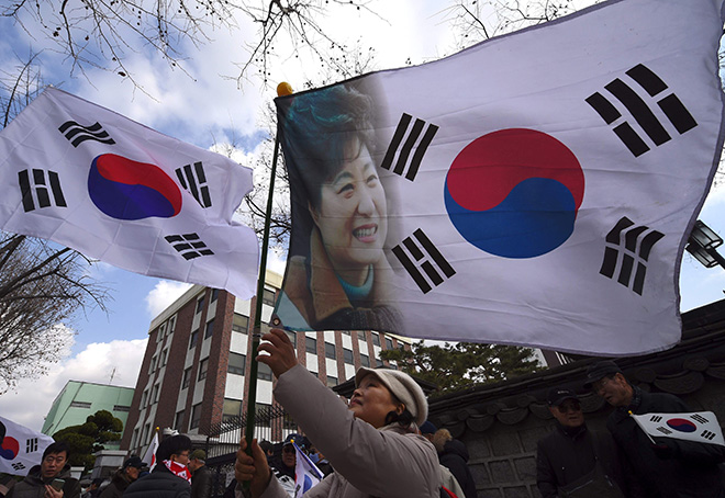  Aktivis prokerajaan mengibarkan bendera negara menunjukkan potret Park ketika menyertai perhimpunan berhampiran Mahkamah Perlembagaan untuk membantah pendakwaan presiden oleh Parlimen dalam skandal rasuah berskala besar di Seoul, kelmarin. — Gambar AFP