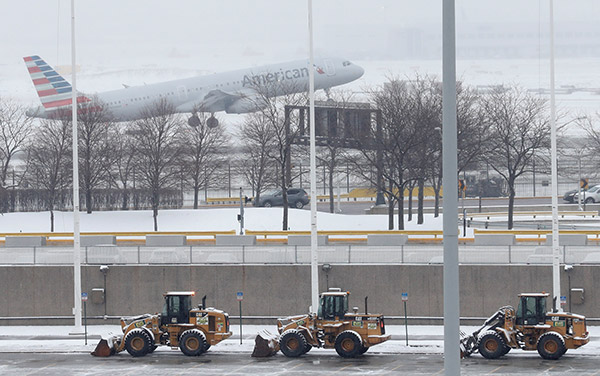  Jentera berat membersihkan salji dari lebuh raya ketika sebuah pesawat American Airlines berlepas dalam ribut salji di Lapangan Terbang Antarabangsa O’Hare di Chicago, Illinois kelmarin. — Gambar Reuters