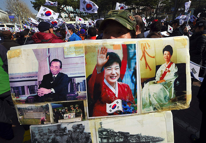  Seorang penyokong menunjukkan kolaj gambar Park (tengah), bapa dan ibunya di luar pejabat pendakwa raya di Seoul, semalam. — Gambar AFP