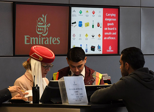  Seorang penumpang membeli tiket di kaunter Emirates Airline berlatarbelakangkan skrin amaran barangan berbahaya di Lapangan Terbang Antarabangsa Los Angeles di Los Angeles, California kelmarin. — Gambar AFP