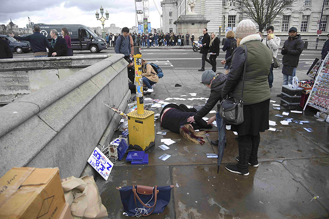  Orang ramai membantu wanita yang cedera selepas serangan di Jambatan Westminster di London kelmarin. — Gambar Reuters