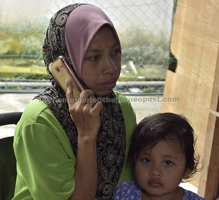  Hariyanti bersama anaknya Nur Ain Sofia membuat panggilan berkongsi berita gembira mengenai pembebasan suaminya Mohd Ridzuan yang diculik kumpulan Abu Sayyaf pada 18 Julai lepas. — Gambar Bernama