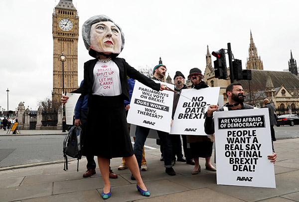  Pembantah Brexit, memakai kepala gergasi Theresa May, memegang plakad di luar Parlimen pada hari perdana menteri mengumumkan beliau secara rasmi memulakan prosedur untuk memisahkan Britain dari EU di London, kelmarin. — Gambar Reuters