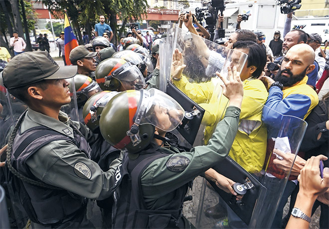  Ahli majlis perundangan pembangkang Carlos Paparoni (tengah) dan Marco Bozo (kanan) bergelut dengan anggota Pengawal Negara semasa tunjuk perasaan di hadapan Mahkamah Agung di Caracas, Venezuela kelmarin. — Gambar AFP