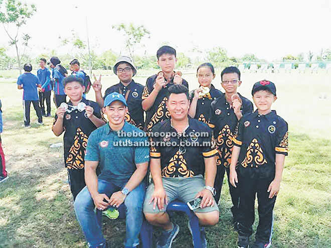  Pasukan pemanah dari Sarawak (berdiri di belakang) gembira menunjukkan medal yang dimenangi bersama Ricky (duduk kanan) di Perlis.