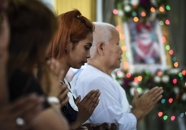  Jiranuch Trirat (tengah) berdoa untuk bayi perempuannya yang berusia                11 bulan, Natalie, di sebuah tokong Buddha di Phuket semalam. — Gambar AFP