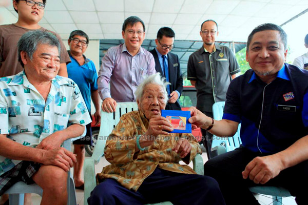  Warga emas Tan Kim Cheng gembira menerima kad pengenalan pemastautin tetap daripada Mohd Yazid (kanan) di Taman Pertama di Taiping, semalam. Tan, 100, dilahirkan di China pada 1917 dan datang ke Malaysia pada 1940. — Gambar Bernama