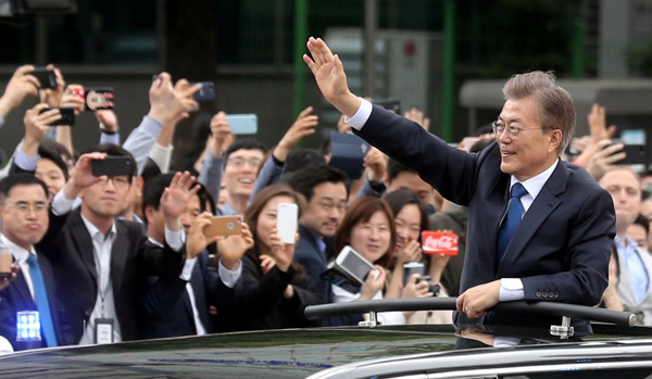  Moon melambaikan tangannya ke arah orang ramai yang berbaris di sepanjang jalan raya dalam perjalanan ke Rumah Biru selepas upacara angkat sumpah jawatan di Seoul, semalam. — Gambar Reuters