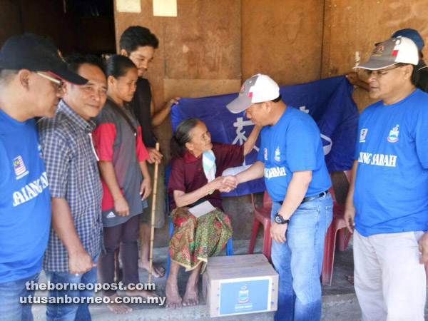  Raime (dua kanan) menyampaikan sumbangan barang keperluan kepada salah seorang penerima di Kg Pangi Seberang. 