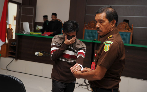  Pegawai (kanan) mengiringi salah seorang tertuduh selesai perbicaraan di Mahkamah Syariah di Banda Aceh, semalam.— Gambar AFP