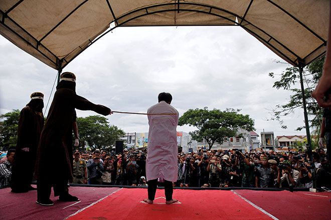  Salah seorang pesalah dalam kes seks gay disebat dengan rotan di khalayak ramai di pekarangan masjid di Banda Aceh, Aceh semalam. — Gambar Reuters