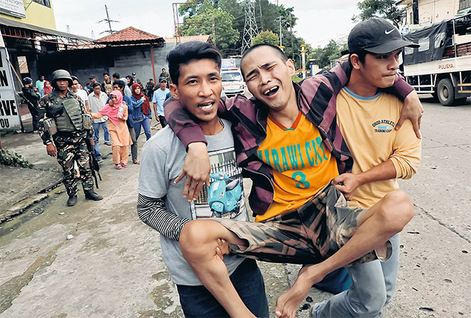  Seorang penduduk dipapah ketika dipindahkan keluar dari bandar Marawi, semalam. — Gambar Reuters-