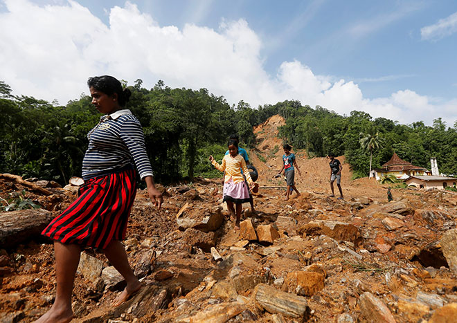  Penduduk meninggalkan kawasan tanah runtuh semasa misi menyelamat di Kampung Athwelthota di Kalutara, semalam. — Gambar Reuters