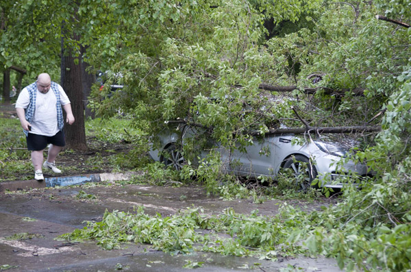  Seorang lelaki melintasi sebuah kereta yang ditimpa pokok tumbang akibat ribut kuat di Moscow, kelmarin. — Gambar Reuters