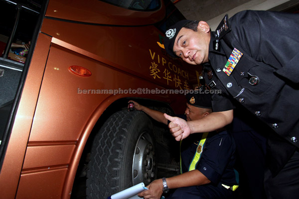  Mazlan menunjukkan isyarat ‘bagus’ ketika meninjau anggota Jabatan Pengangkutan Jalan (JPJ) memeriksa tayar hadapan bas ekspres semalam. — Gambar Bernama