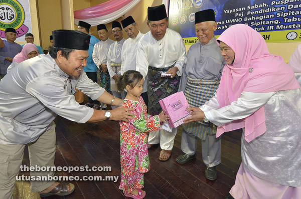  Patimah (kanan) bersama Sapawi (tiga kanan) menyampaikan sumbangan kepada salah seorang anak yatim.