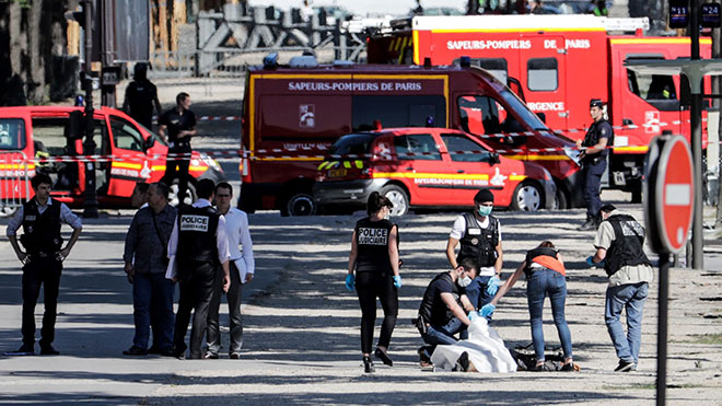  Pegawai polis menjalankan siasatan ke atas mayat suspek yang ditutup dengan kain putih di tempat kejadian yang telah disita di lebuh Champs-Elysees di Paris, kelmarin. — Gambar AFP