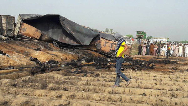  Penduduk setempat berkumpul untuk melihat lebih seratus mayat rentung di sebelah lori tangki minyak yang meletup selepas terbalik di lebuh raya dekat bandar Ahmedpur Timur, kira-kira 670 kilometer dari Islamabad, Pakistan kelmarin. — Gambar AFP