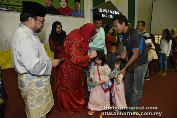  Rahim (kiri) dan Rosnah menyampaikan duit raya kepada kanak-kanak yang hadir pada majlis itu.