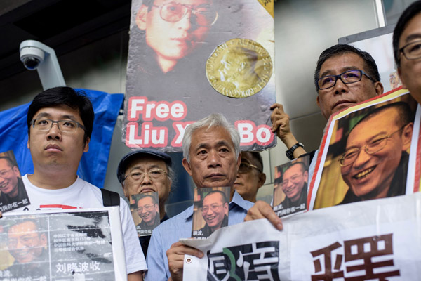  Penunjuk perasaan memaparkan poskad yang ditujukan buat Liu (gambar pada kad) di luar Pejabat Pos Umum di Hong Kong, semalam. — Gambar AFP