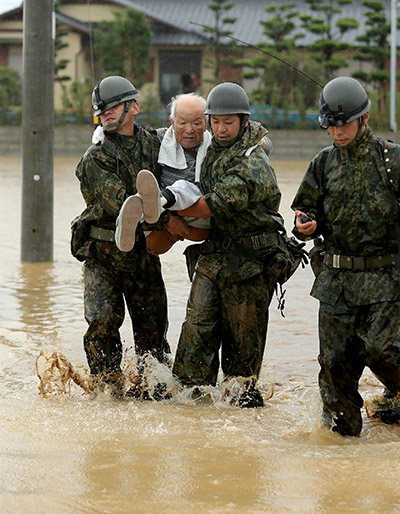  Gambar serahan Jiji Press menunjukkan tentera Jepun mengangkat seorang lelaki tua ketika mereka membantu penduduk setempat berpindah dari kawasan dilanda                                  banjir besar di Asakura, daerah Fukuoka di selatan Jepun semalam. — Gambar AFP
