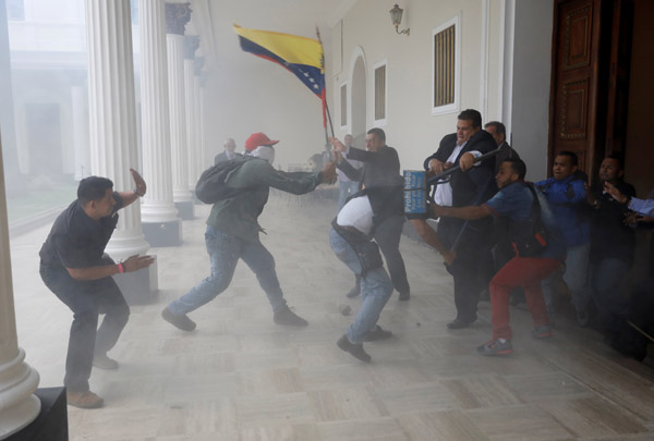  Penyokong kerajaan memegang bendera negara             ketika bertempur dengan anggota perundangan di luar Dewan Negara di Caracas, Venezuela kelmarin. — Gambar Reuters