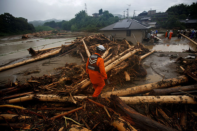  Seorang anggota penyelamat berjalan di atas serpihan kayu yang dihanyutkan hujan lebat ketika operasi mencari orang hilang berhampiran sebuah rumah yang rosak akibat banjir besar di daerah Yamada di Asakura, wilayah Fukuoka, Jepun semalam. — Gambar Reuters