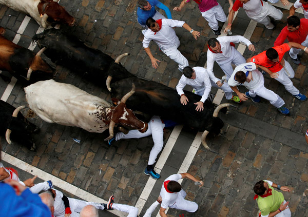  Seorang pelari terjatuh di hadapan sekawan lembu jantan yang naik minyak pada hari keempat Festival San Fermin di Pamplona, utara Sepanyol semalam. — Gambar Reuters