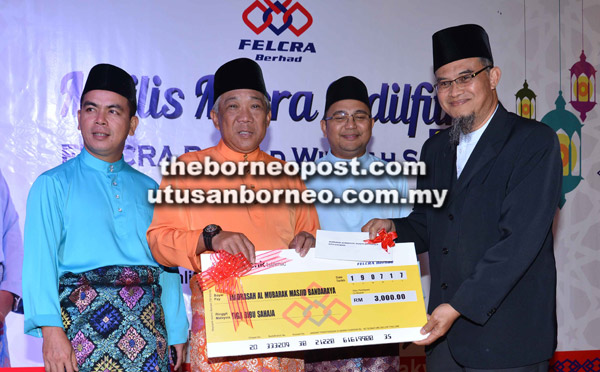  Bung (dua kiri) menyampaikan replika cek kepada Pengetua Madrasah Al-Mubarak Ahmad Sabari Kamari (kanan) pada majlis berkenaan.