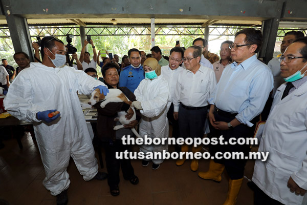  Abang Johari (dua kanan) melihat dengan dekat pegawai veterinar menyuntik vaksin pada seekor anjing semasa operasi pemvaksinan wabak rabies di Dewan Masyarakat Batu 10, Kuching semalam. Turut kelihatan Uggah (tiga kanan) dan Dr Sim (empat kanan).