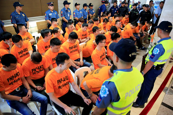  Anggota polis berkawal di sekeliling suspek, majoriti warga China yang ditangkap kerana disyaki menculik seorang wanita Singapura di sebuah kasino, di Ibu Pejabat Polis Negara Filipina di Manila, semalam. — Gambar Reuters