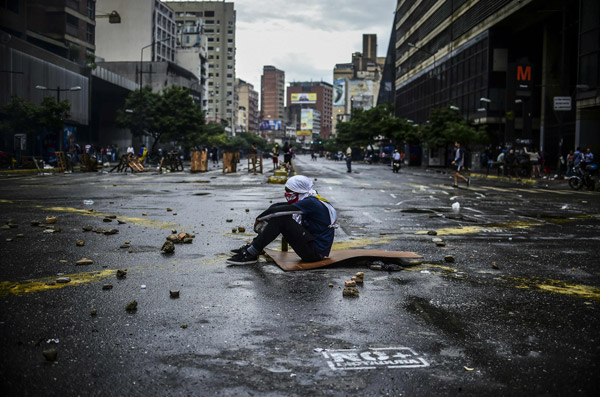  Aktivis bertopeng duduk di atas jalan raya ketika memprotes terhadap Maduro di Caracas, kelmarin. — Gambar AFP