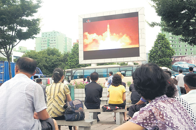  Penduduk Korea Utara menyaksikan pelancaran ujian misil ICBM yang dipaparkan pada skrin gergasi di dataran awam di Pyongyang, semalam. — Gambar AFP