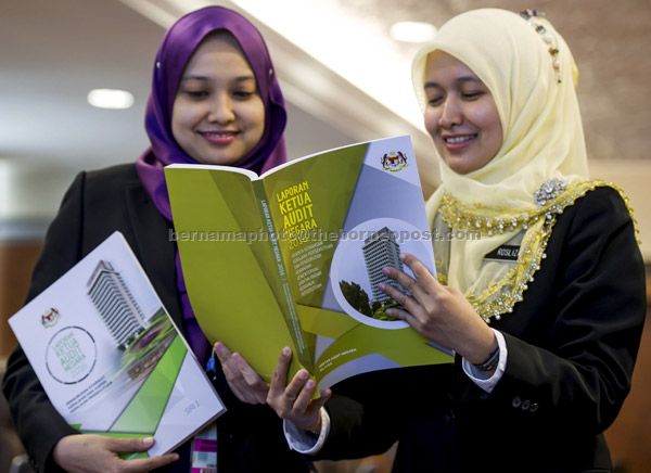  Kakitangan Jabatan Audit Negara Rosliza Razi (kanan) dan Siti Zulaiha                                    Mustapar melihat Buku Laporan Ketua Audit Negara Tahun 2016 Siri 1 di Bangunan Parlimen                    di Kuala Lumpur semalam. — Gambar Bernama