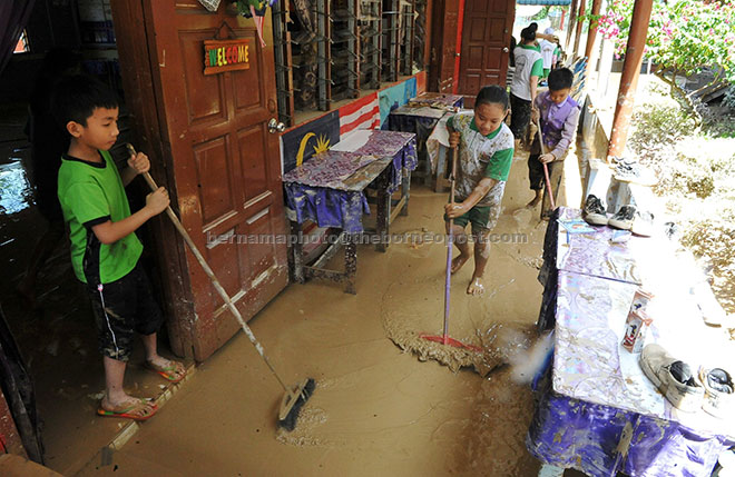  Murid-murid SRK Darau Menggatal membersihkan sekolah mereka yang teruk dilanda banjir berikutan hujan semalam. — Gambar Bernama 