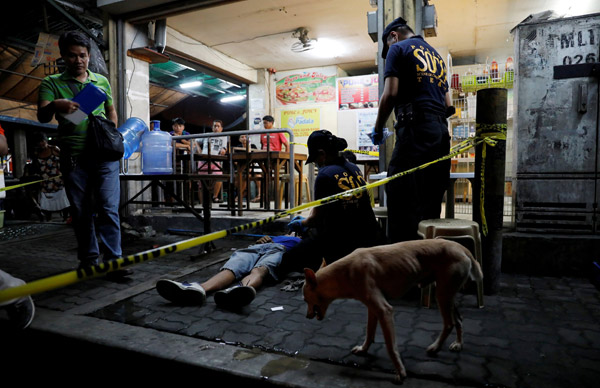  Pegawai polis memeriksa mayat seorang lelaki yang menurut mereka ditembak mati dalam pembunuhan berkaitan dadah di Manila, Filipina kelmarin. — Gambar Reuters