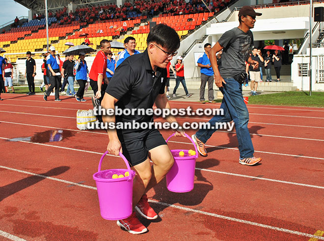  Peserta dari Kumpulan KTS mengangkat baldi yang berisi air dan bola ping pong dalam satu acara sukaneka yang diadakan pada festival itu.