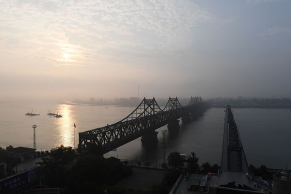 Bandar Korea Utara Sinuiju melatari pemandangan di seberang Jambatan Persahabatan (kiri) yang menghubungkannya dengan bandar sempadan China Dandong, dan Jambatan Patah di Dandong dalam wilayah timur laut Liaoning semalam. — Gambar AFP