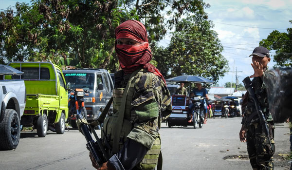  Seorang anggota MILF dengan muka bertutup ditemani seorang askar kerajaan (kanan) ketika memantau pos pemeriksaan mudah alih di Datu Salibo, Maguindanao kelmarin. — Gambar AFP