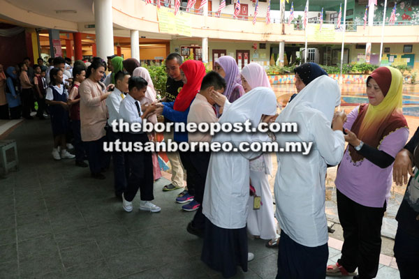  Calon Ujian Pencapaian Sekolah Rendah, Sekolah Kebangsaan Dato Traoh di Kota Samarahan bersalaman dengan ibu bapa dan guru.