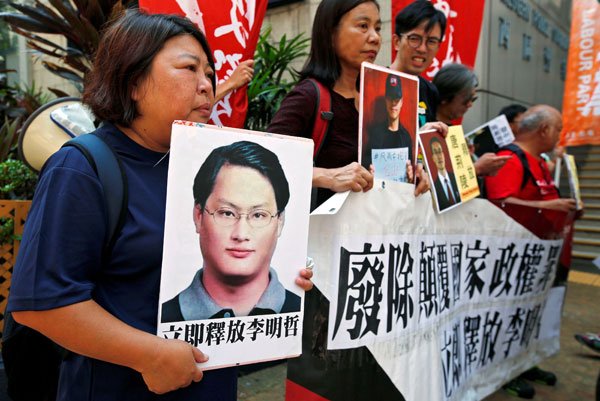  Penunjuk perasaan membawa gambar Lee (kiri) dan aktivis lain semasa mengadakan demonstrasi di Hong Kong, semalam. — Gambar Reuters