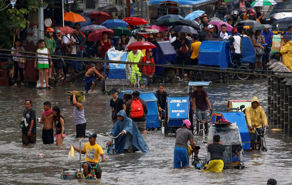  Penduduk menunggu giliran untuk meredah banjir menggunakan beca teksi di Las Pinas, Metro Manila ketika ribut membadai pulau utama Luzon semalam. — Gambar Reuters