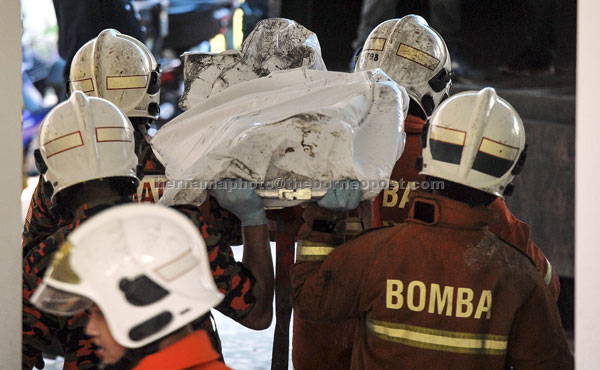  Anggota bomba mengusung jenazah mangsa kebakaran. — Gambar Bernama