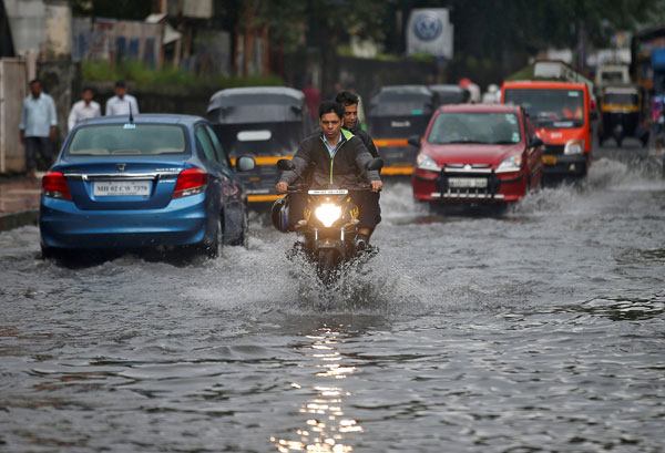  Orang ramai meredah jalan yang ditenggelami air setelah hujan lebat di Mumbai, semalam. — Gambar Reuters