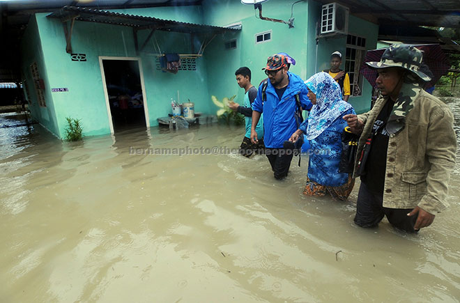  Penduduk kampung membantu seorang warga emas mengharungi banjir kilat berikutan hujan lebat di Kampung Kulup, Teluk Kumbar di George Town semalam. — Gambar Bernama