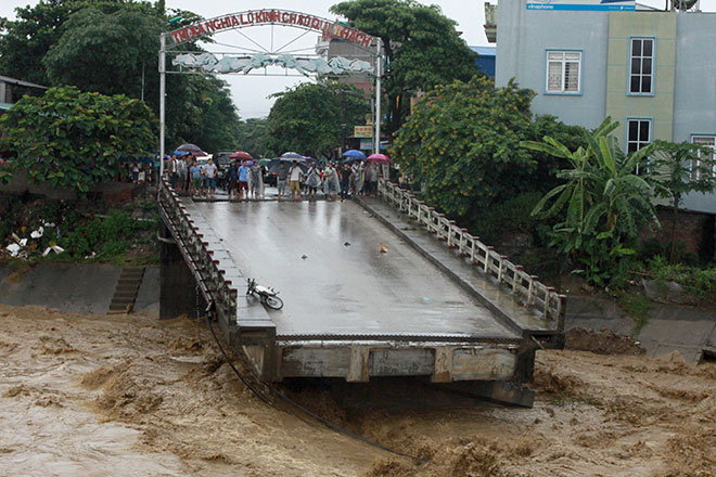  Penduduk dilihat berkumpul di hujung jambatan yang runtuh akibat banjir di Yen Bai, Vietnam kelmarin. — Gambar AFP